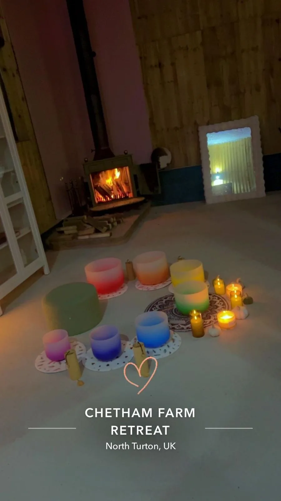Colourful soundbath bowls arranged by candlelight in front of the fire at Chetham Farm Retreat